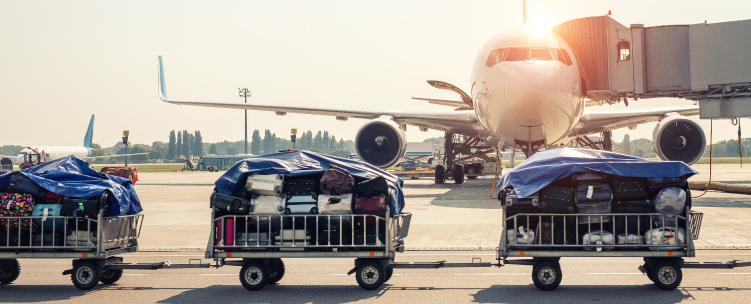 Suitcases are transported across the tarmac on a trollies linked together like a train.
