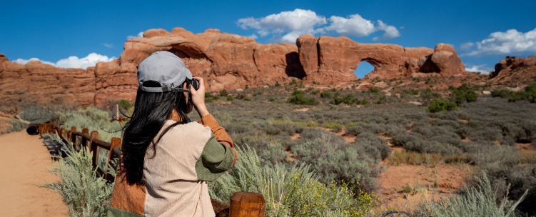 A Woman photographs red rock formations in a US desert